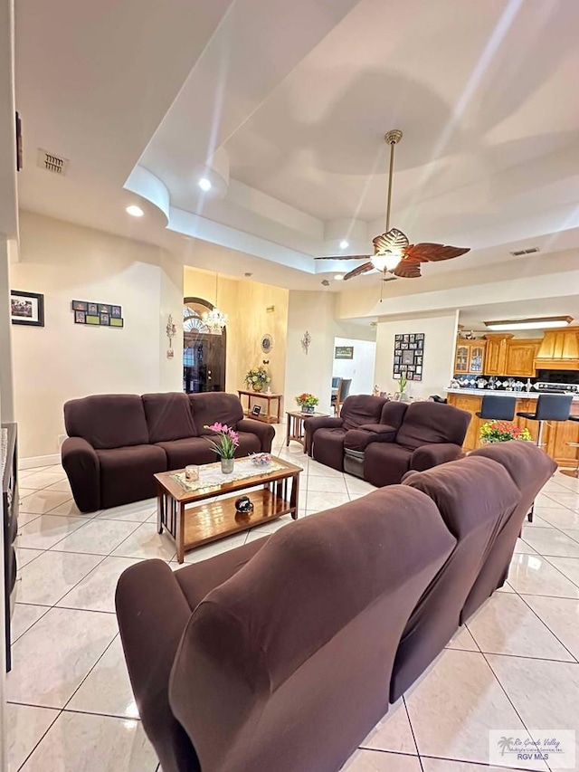 living room with ceiling fan, light tile patterned flooring, recessed lighting, visible vents, and a tray ceiling