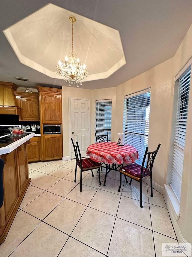 dining space with light tile patterned floors, a raised ceiling, visible vents, and a chandelier