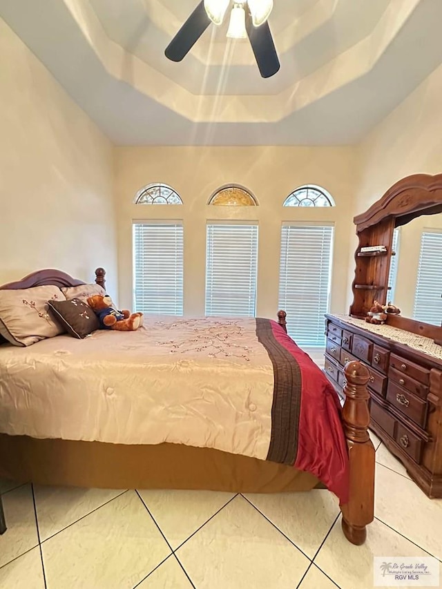 bedroom with a ceiling fan, tile patterned flooring, and a raised ceiling