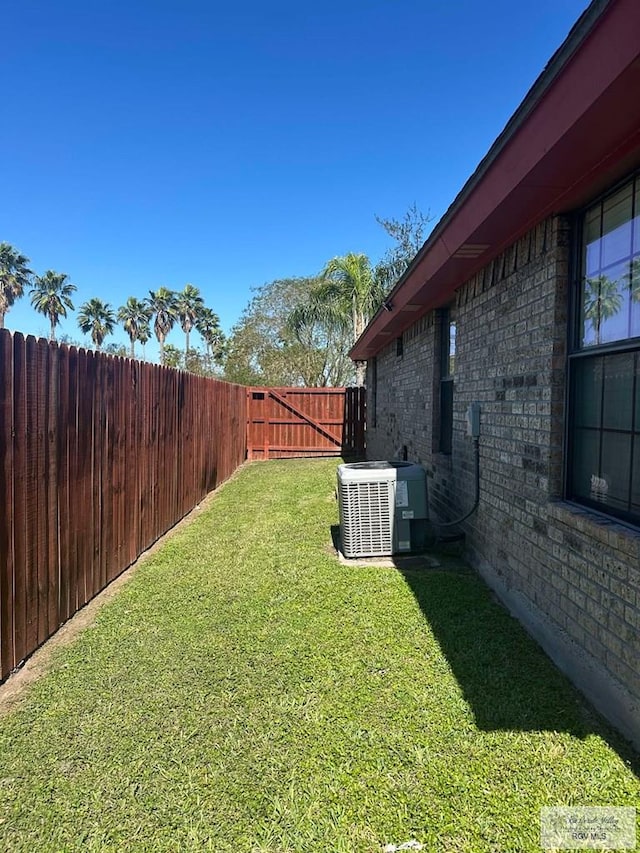 view of yard with a fenced backyard and central AC unit