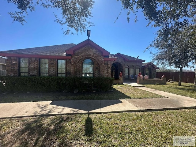 single story home featuring brick siding, fence, and a front yard