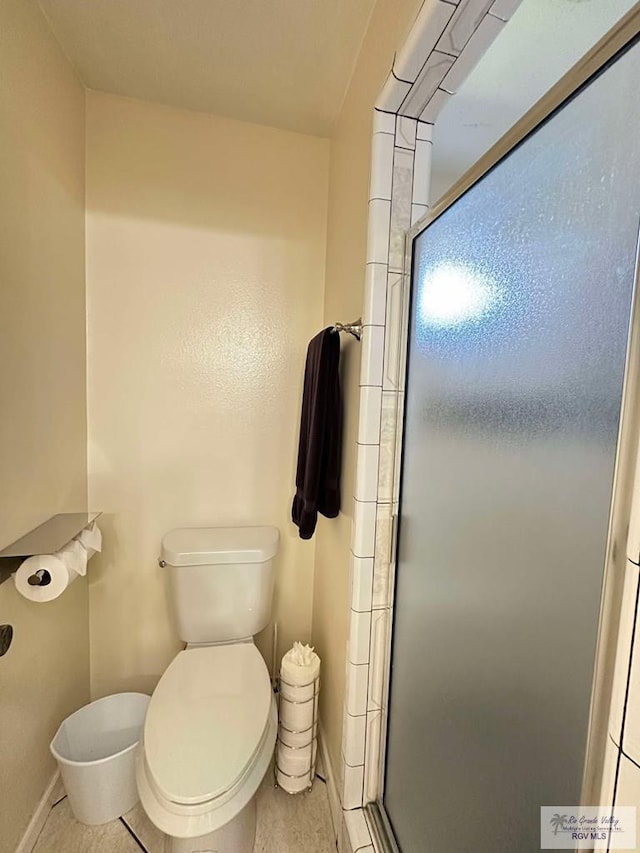 full bathroom featuring toilet, a shower stall, and baseboards