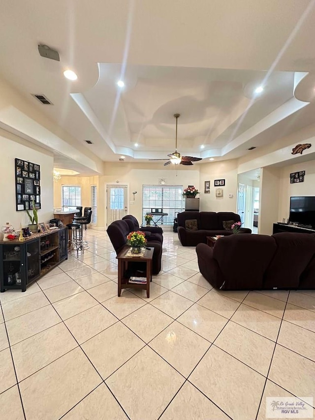 living room featuring a raised ceiling, light tile patterned flooring, and a healthy amount of sunlight