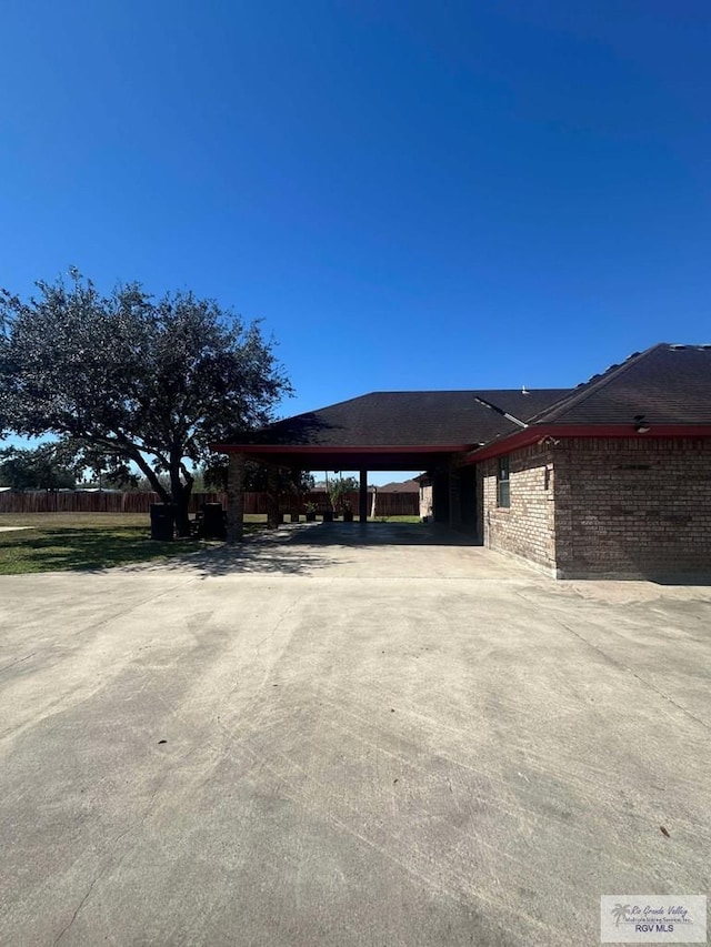 exterior space with a carport, brick siding, and fence