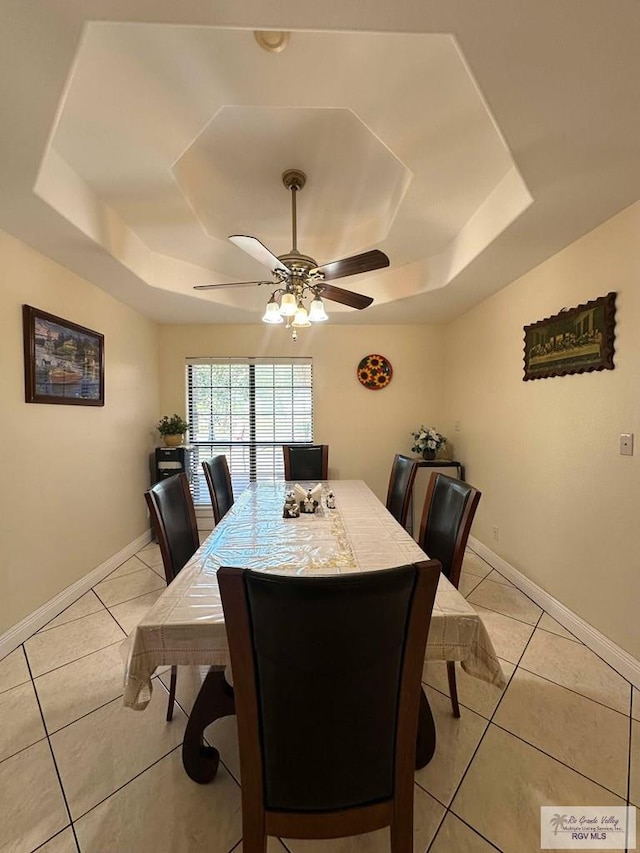 dining room with ceiling fan, baseboards, a raised ceiling, and light tile patterned flooring