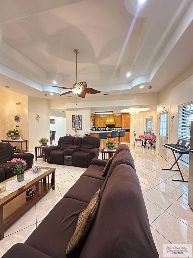 living room with light tile patterned floors, a raised ceiling, a ceiling fan, and recessed lighting