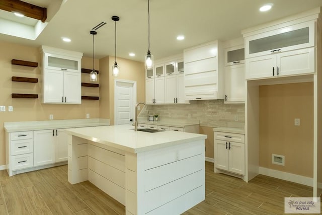 kitchen featuring a sink, open shelves, light wood-type flooring, decorative light fixtures, and decorative backsplash