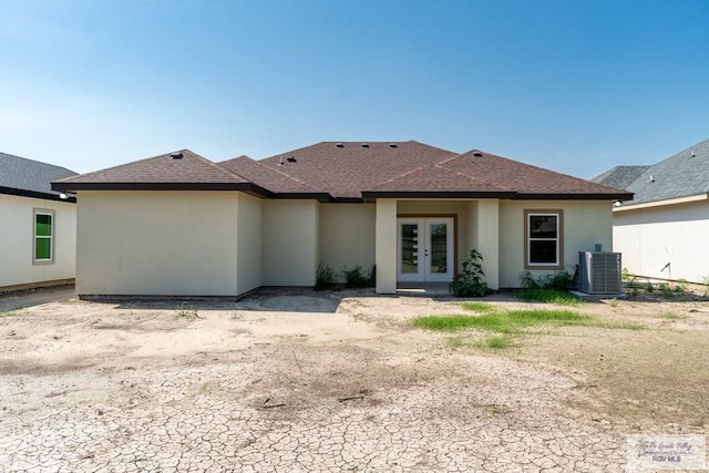 rear view of house featuring stucco siding, a shingled roof, and french doors