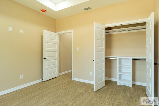unfurnished bedroom featuring baseboards, visible vents, a closet, and light wood-style floors
