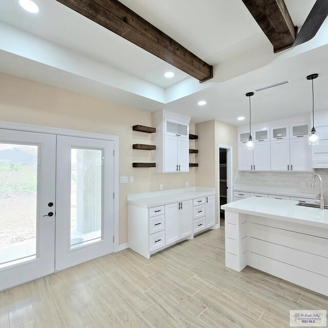 kitchen with white cabinetry, french doors, hanging light fixtures, and beamed ceiling