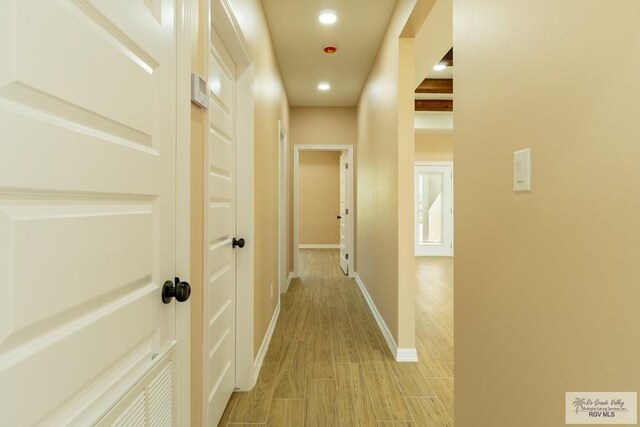 hallway featuring baseboards, light wood-style floors, and recessed lighting