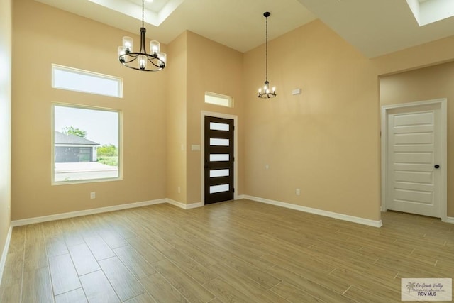 foyer featuring baseboards, light wood-type flooring, and a notable chandelier