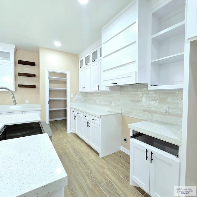 kitchen featuring light stone countertops, white cabinets, and decorative backsplash