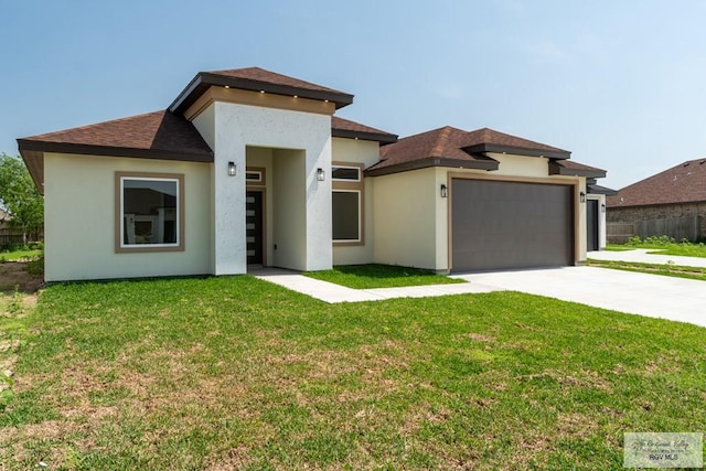 prairie-style house with driveway, an attached garage, stucco siding, and a front yard