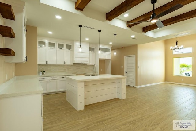 kitchen with open shelves, ceiling fan with notable chandelier, decorative backsplash, a sink, and light wood-style floors