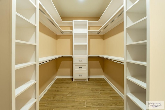 spacious closet with built in desk and wood tiled floor