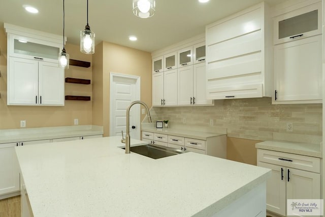 kitchen with white cabinetry, recessed lighting, decorative backsplash, a sink, and an island with sink