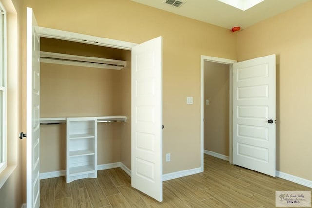 unfurnished bedroom with baseboards, a closet, and wood tiled floor