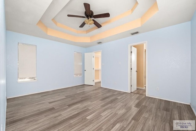 3673 Rey Enrique Dr, Brownsville, TX 78521 - unfurnished bedroom with a tray ceiling, wood finished floors, baseboards, connected bathroom, and a ceiling fan