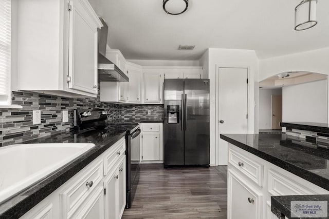 3673 Rey Enrique Dr, Brownsville, TX 78521 - kitchen with stainless steel fridge with ice dispenser, black range with electric cooktop, arched walkways, wall chimney range hood, and decorative backsplash