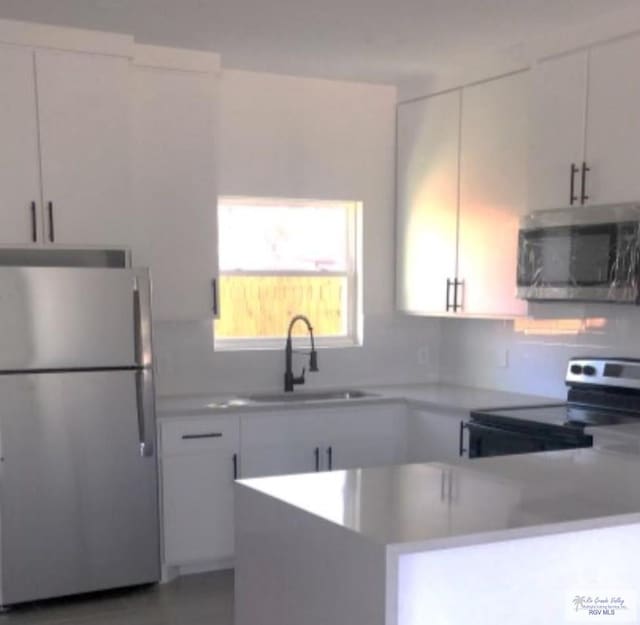 kitchen featuring decorative backsplash, stainless steel appliances, white cabinetry, and sink