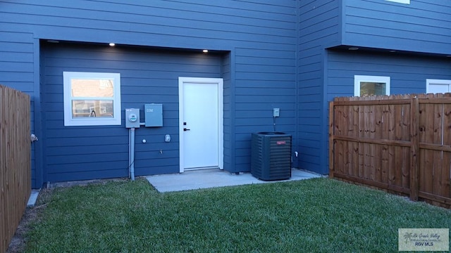 rear view of house with central AC unit and a lawn