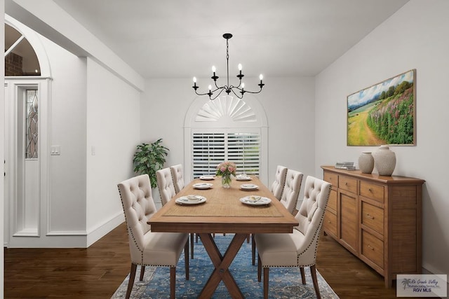 dining space featuring dark wood-type flooring and a notable chandelier