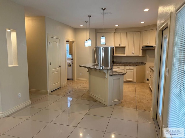 kitchen with pendant lighting, stainless steel fridge, dark stone countertops, light tile patterned floors, and a kitchen island