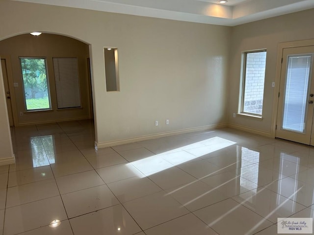 tiled spare room featuring a healthy amount of sunlight