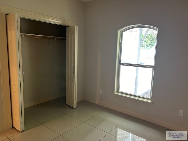 unfurnished bedroom featuring light tile patterned floors and a closet