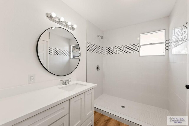 bathroom with a tile shower, vanity, and hardwood / wood-style flooring