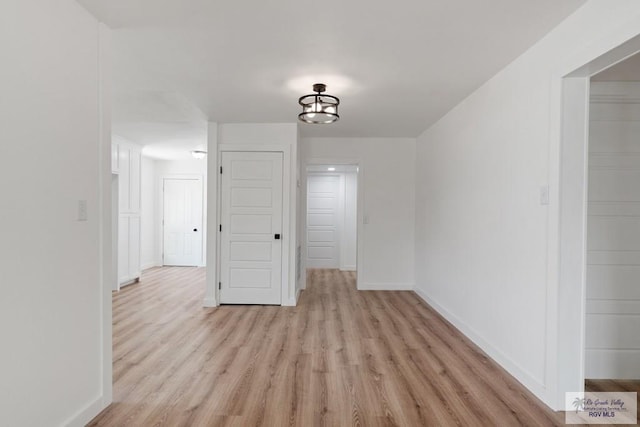 empty room with a notable chandelier and light wood-type flooring