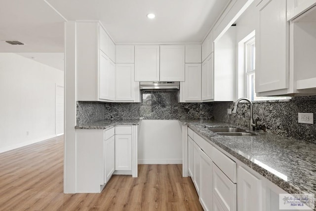 kitchen featuring backsplash, sink, range hood, light hardwood / wood-style floors, and white cabinetry