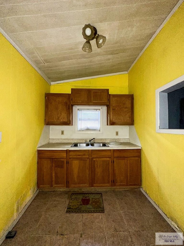 kitchen featuring crown molding, sink, and lofted ceiling