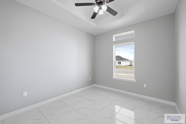 unfurnished room with ceiling fan and a raised ceiling