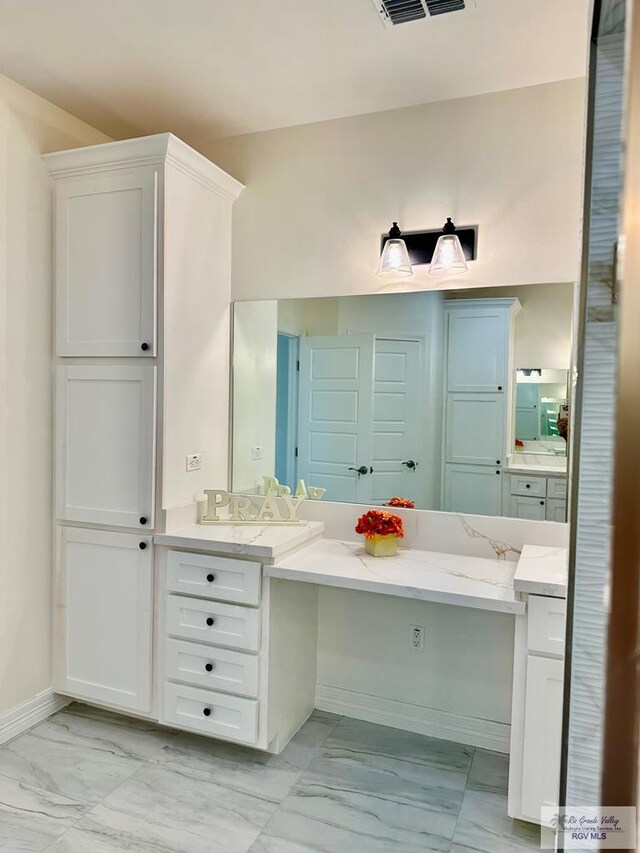 kitchen with white cabinetry, light stone countertops, sink, and decorative light fixtures