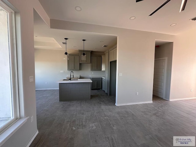 kitchen with a wealth of natural light, hanging light fixtures, a center island with sink, and gray cabinetry