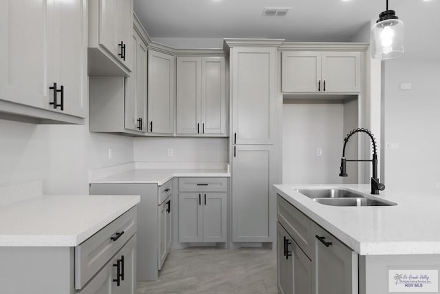 kitchen with gray cabinetry, sink, and hanging light fixtures