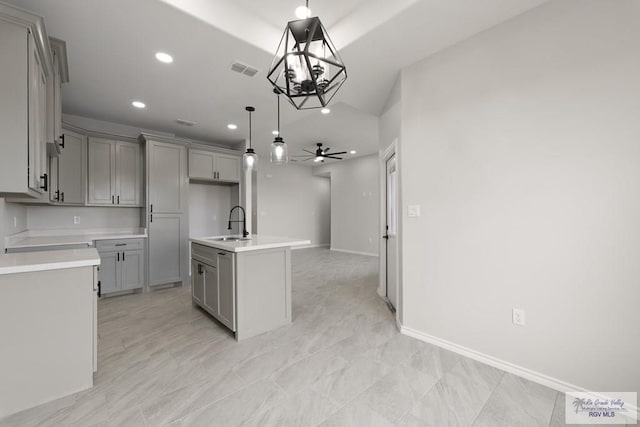 kitchen featuring pendant lighting, sink, ceiling fan, gray cabinetry, and an island with sink