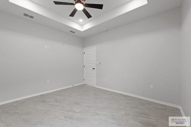 spare room with a raised ceiling and ceiling fan