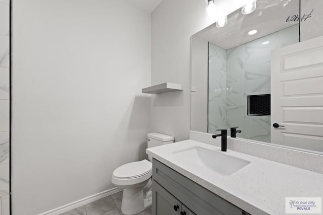 bathroom with vanity, a tile shower, and toilet