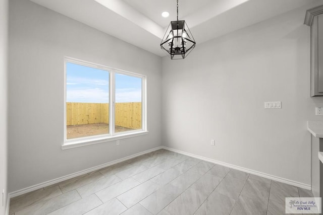 unfurnished dining area with a raised ceiling and an inviting chandelier