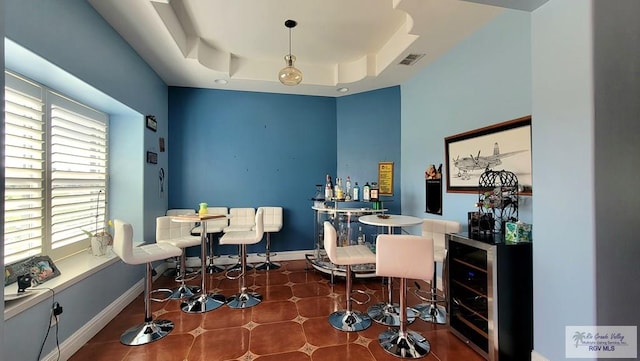 home office with dark tile patterned flooring, indoor bar, wine cooler, and a tray ceiling