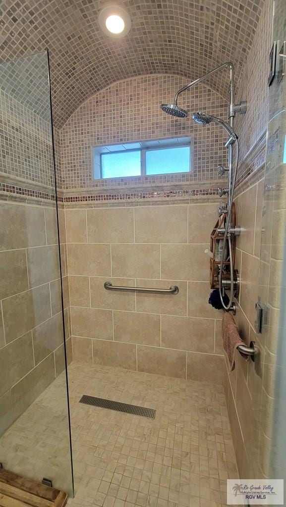 bathroom featuring a tile shower and vaulted ceiling