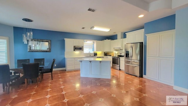 kitchen with white cabinets, decorative light fixtures, sink, and stainless steel appliances