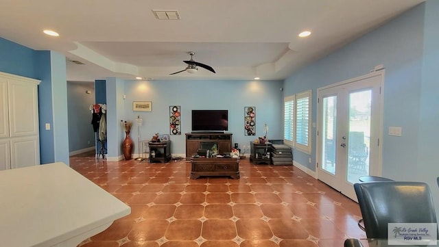 living room featuring french doors, a raised ceiling, and ceiling fan