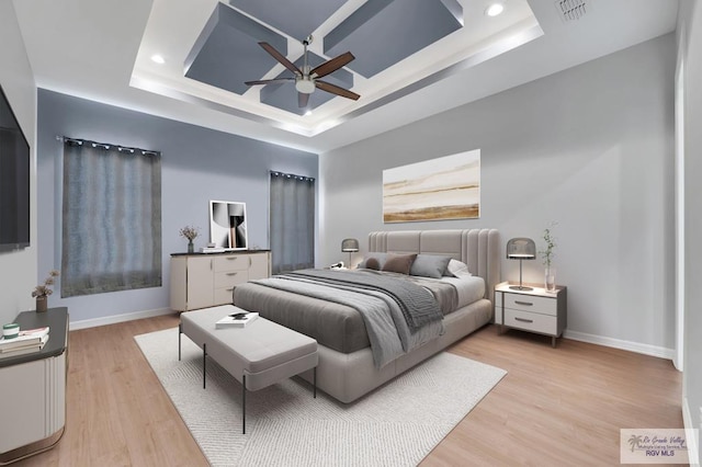 bedroom with ceiling fan, a raised ceiling, and light hardwood / wood-style flooring