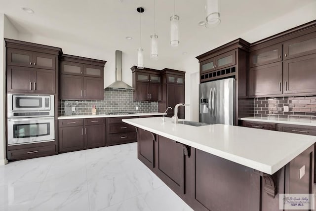 kitchen with decorative backsplash, sink, wall chimney exhaust hood, and appliances with stainless steel finishes