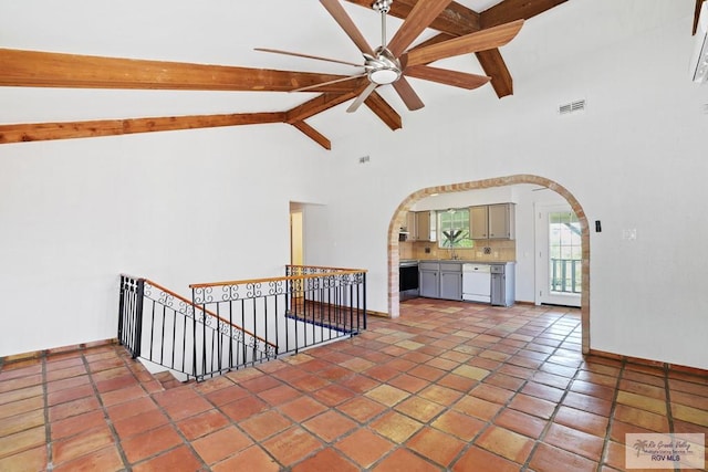 empty room featuring visible vents, baseboards, ceiling fan, beamed ceiling, and arched walkways