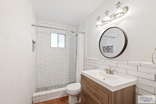 bathroom featuring toilet, tile walls, a stall shower, and vanity